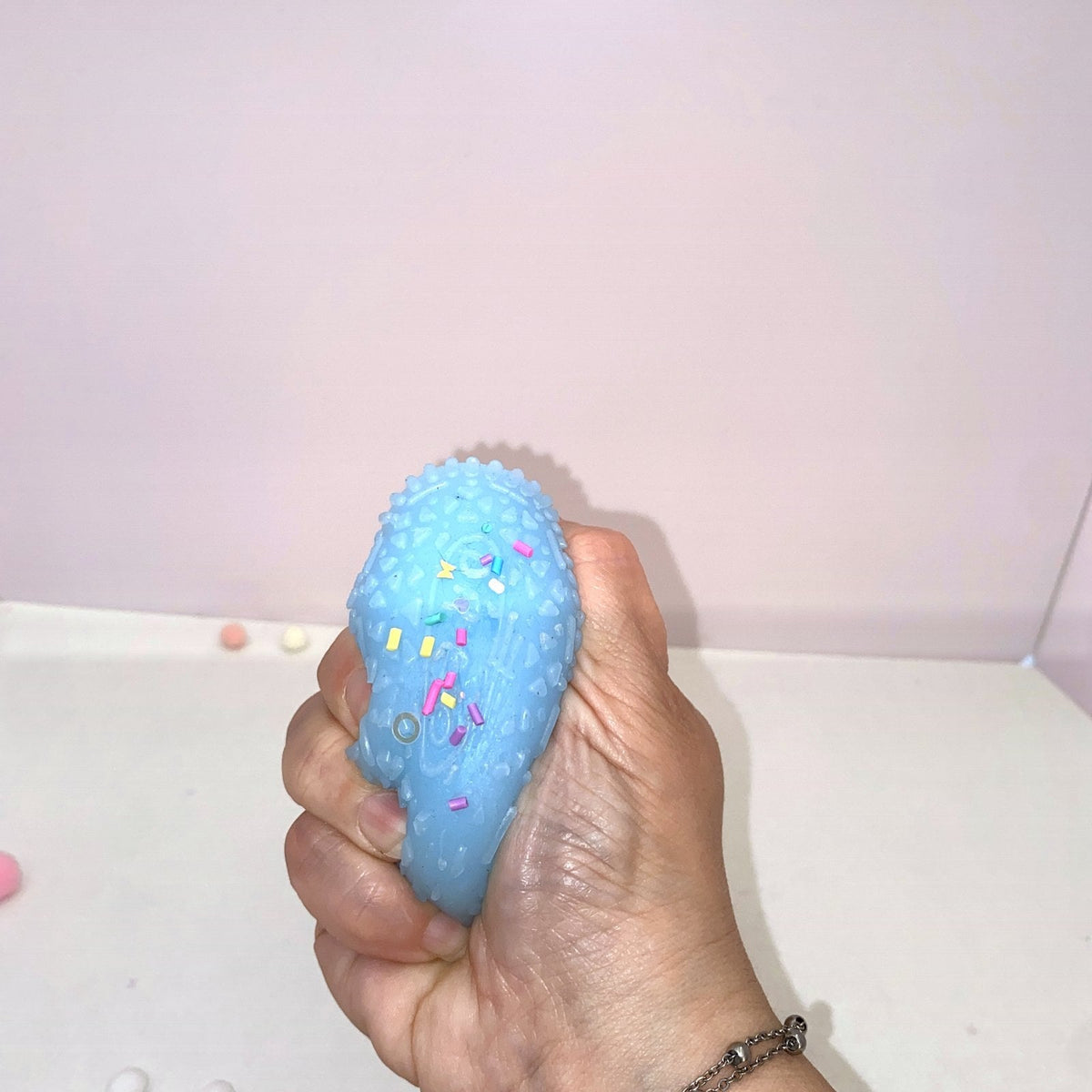 Squishy cookie bleu CLADEA écrasé dans la main, démonstration du retour lent