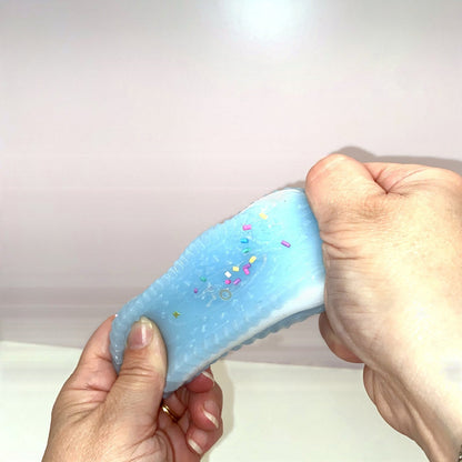 Squishy cookie bleu CLADEA étiré entre les mains, démonstration de l'élasticité