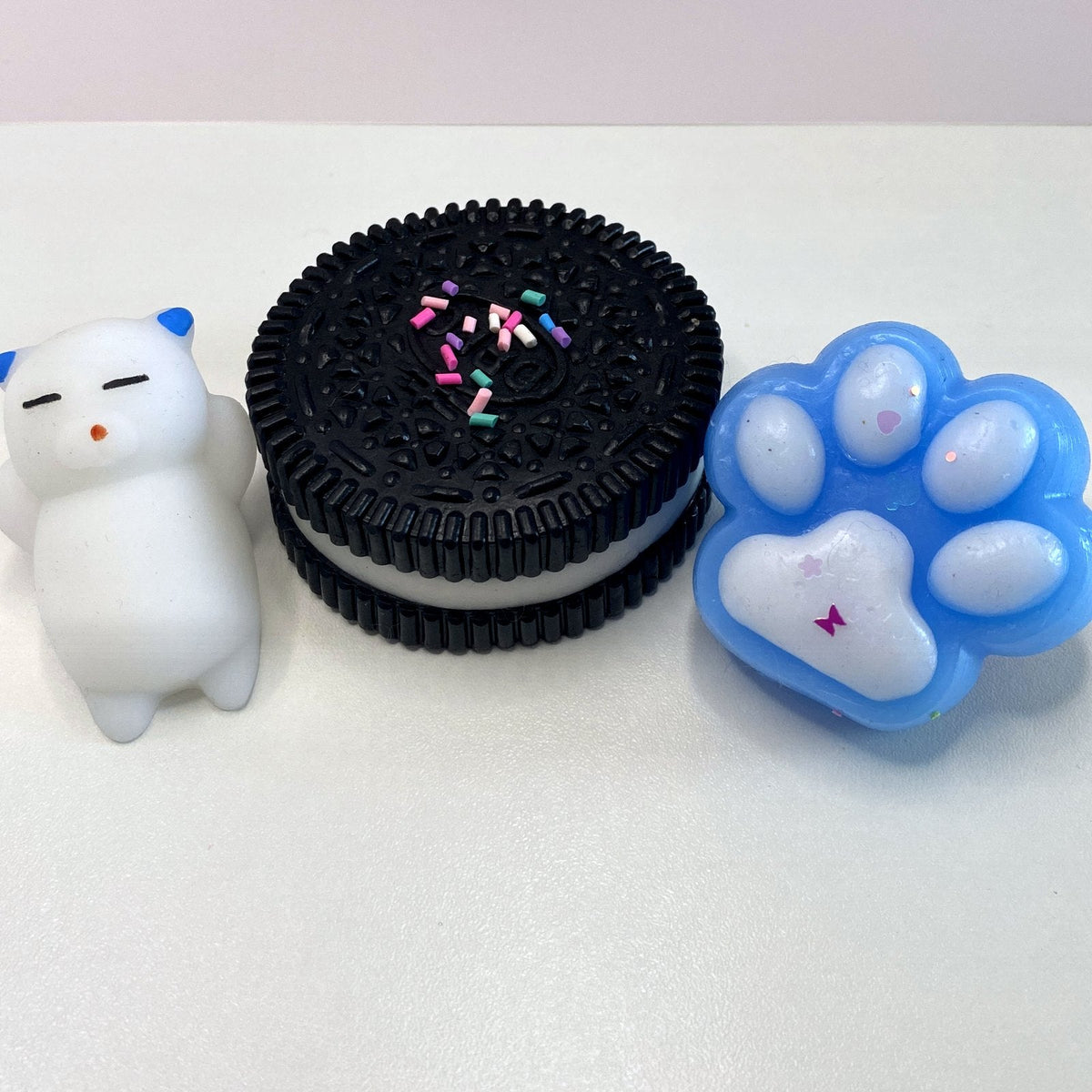 Pack 3 squishys CLADEA : cookie noir, patte de chat bleue et chaton blanc
