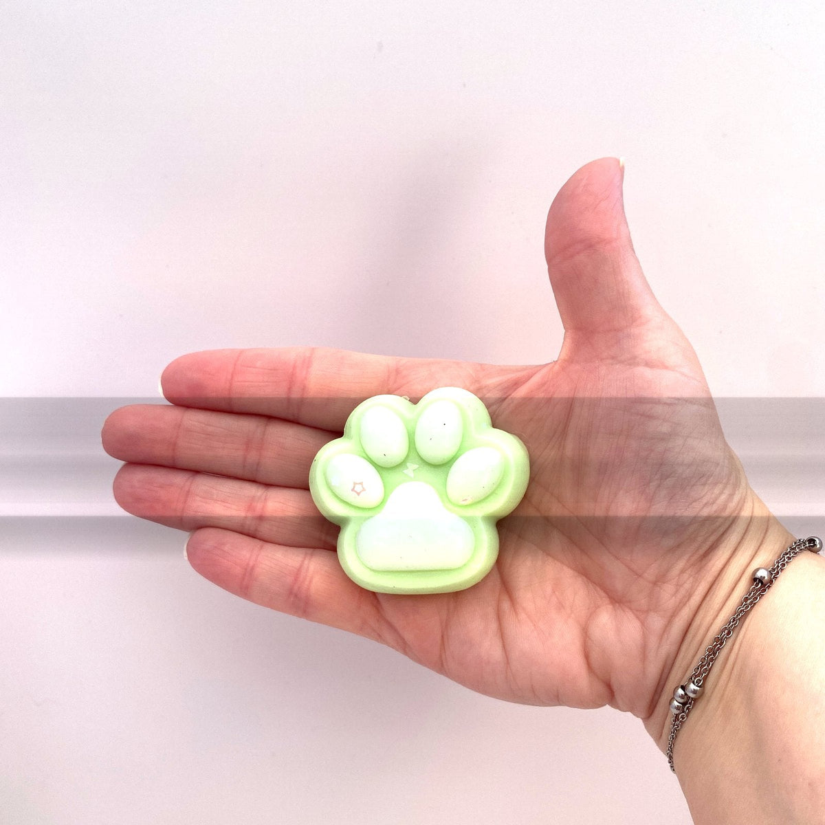 Taille du squishy patte de chat verte CLADEA dans la paume d'une main